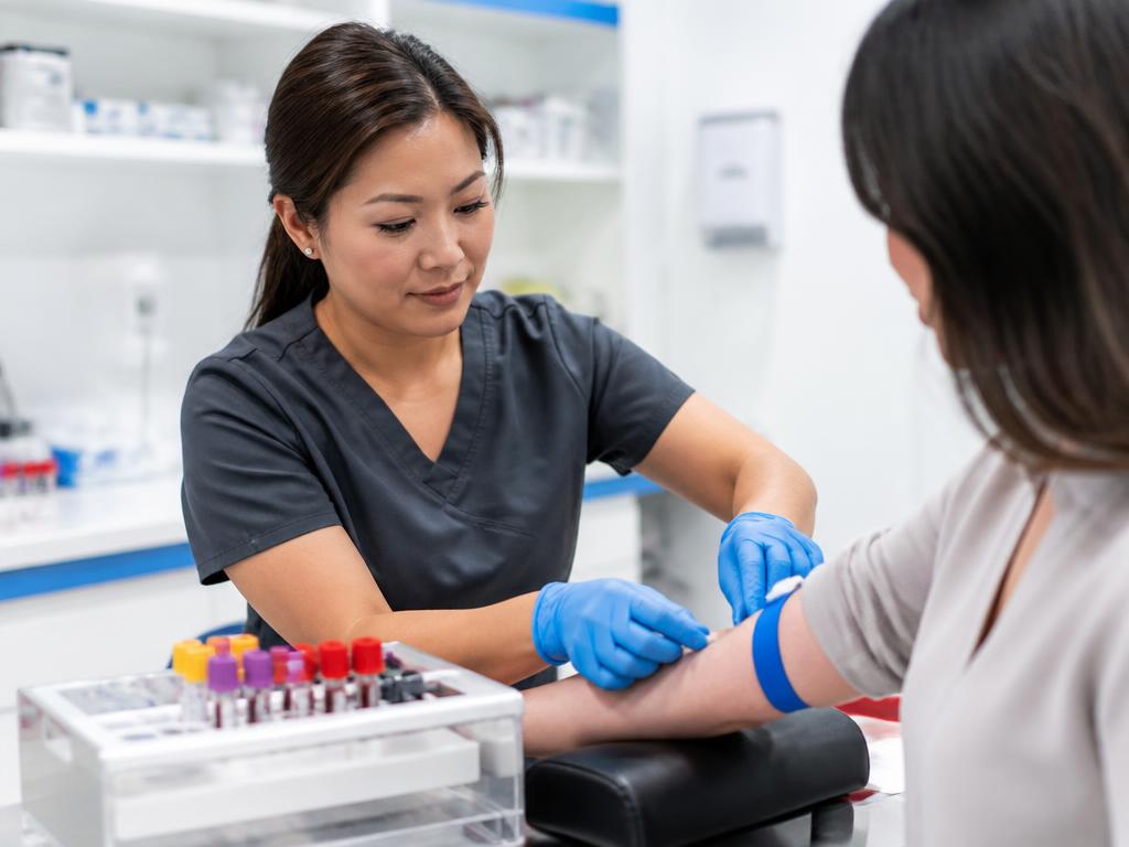 Phlebotomy technician performing a blood draw in a clinical lab